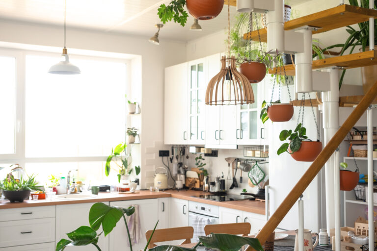 The interior of a white kitchen with a metal staircase in a cott