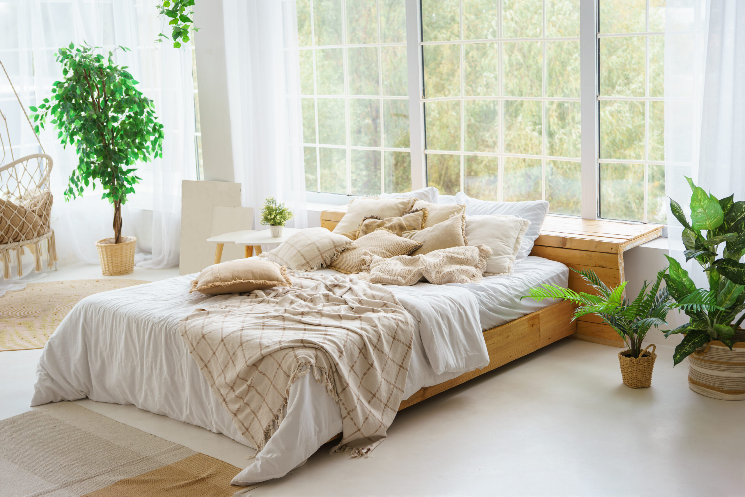 Comfortable bed with lots of soft decorative beige pillows in li