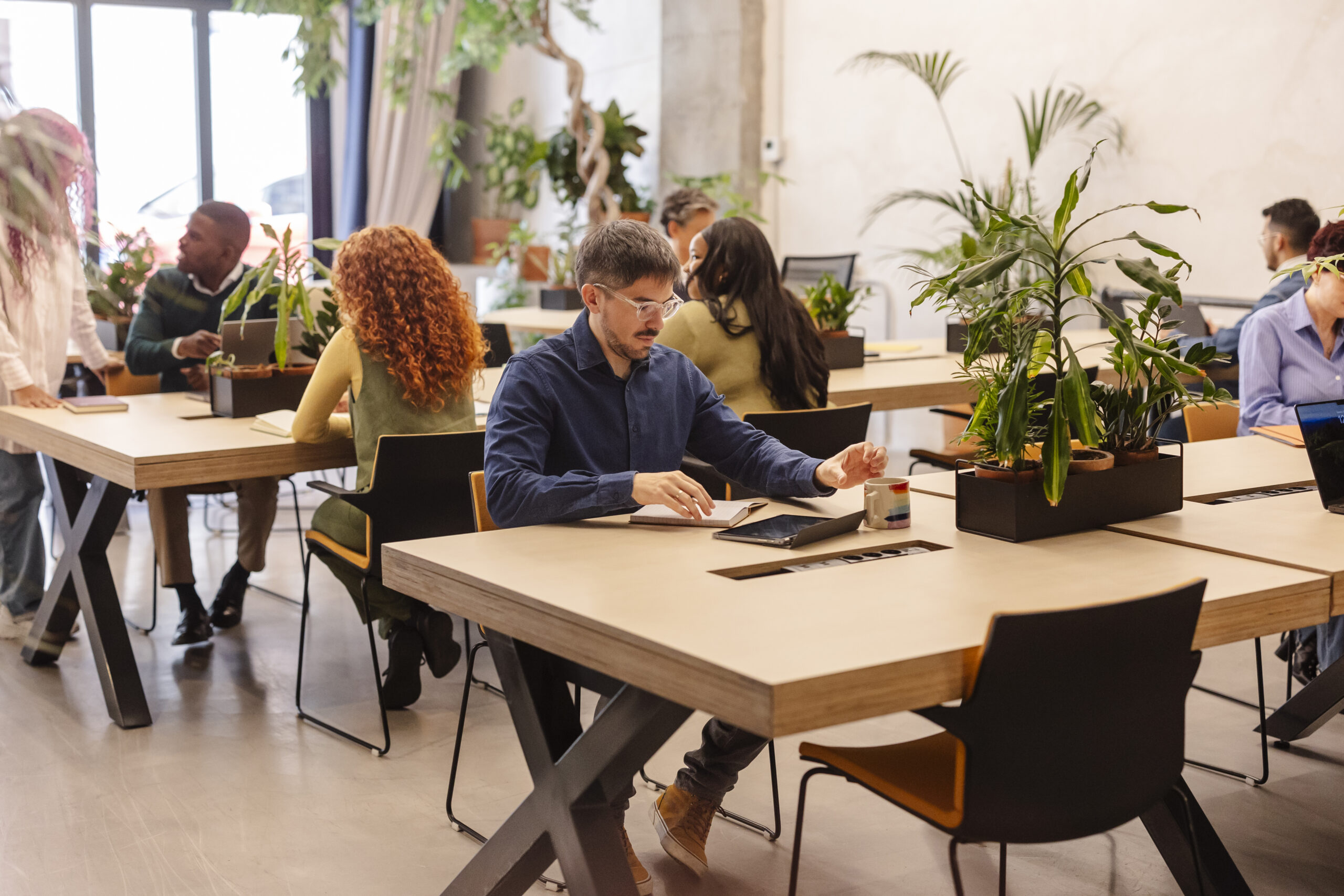 Focused employee working in modern green office with diverse colleagues