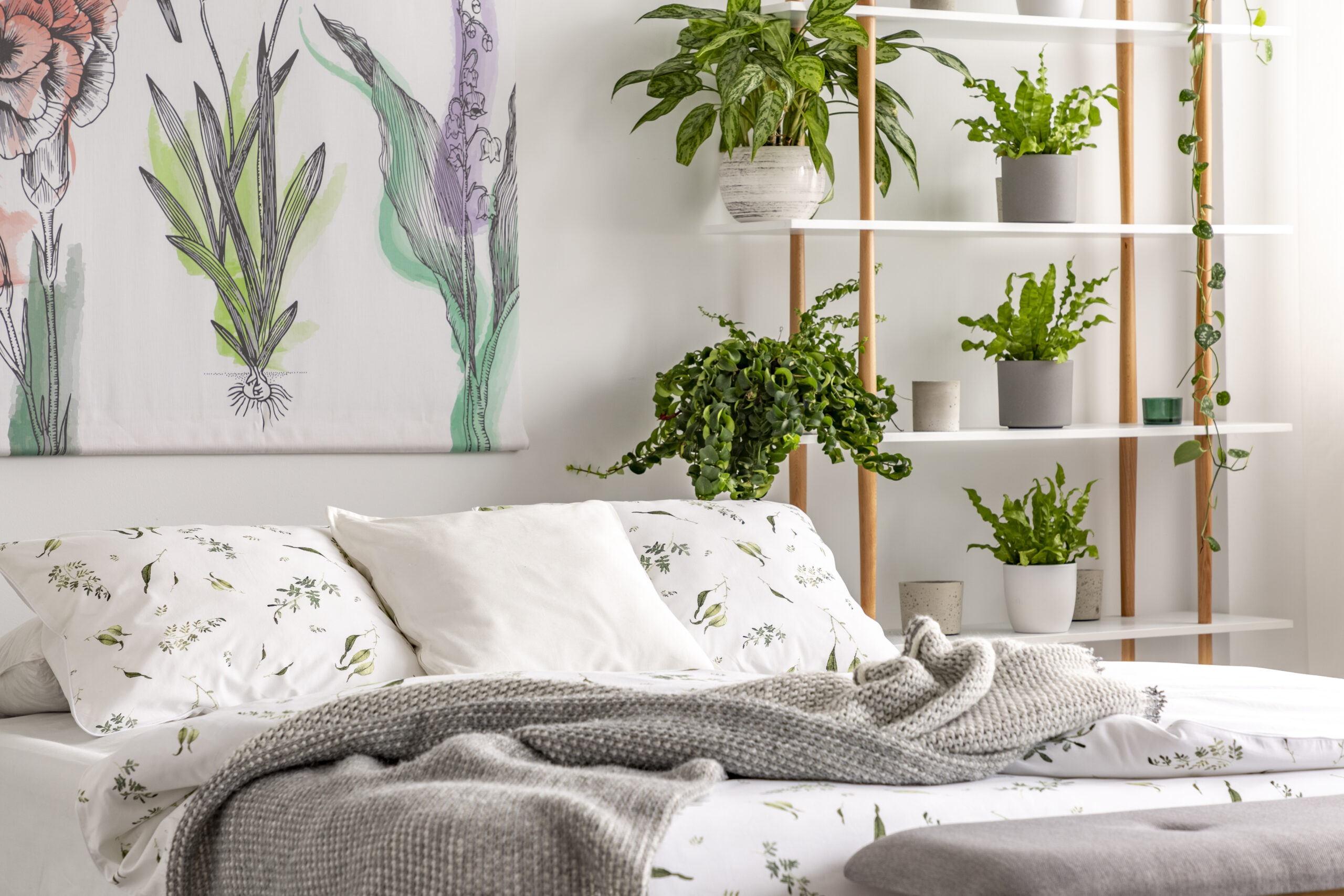 Urban jungle bedroom interior with plants in pots beside a bed d